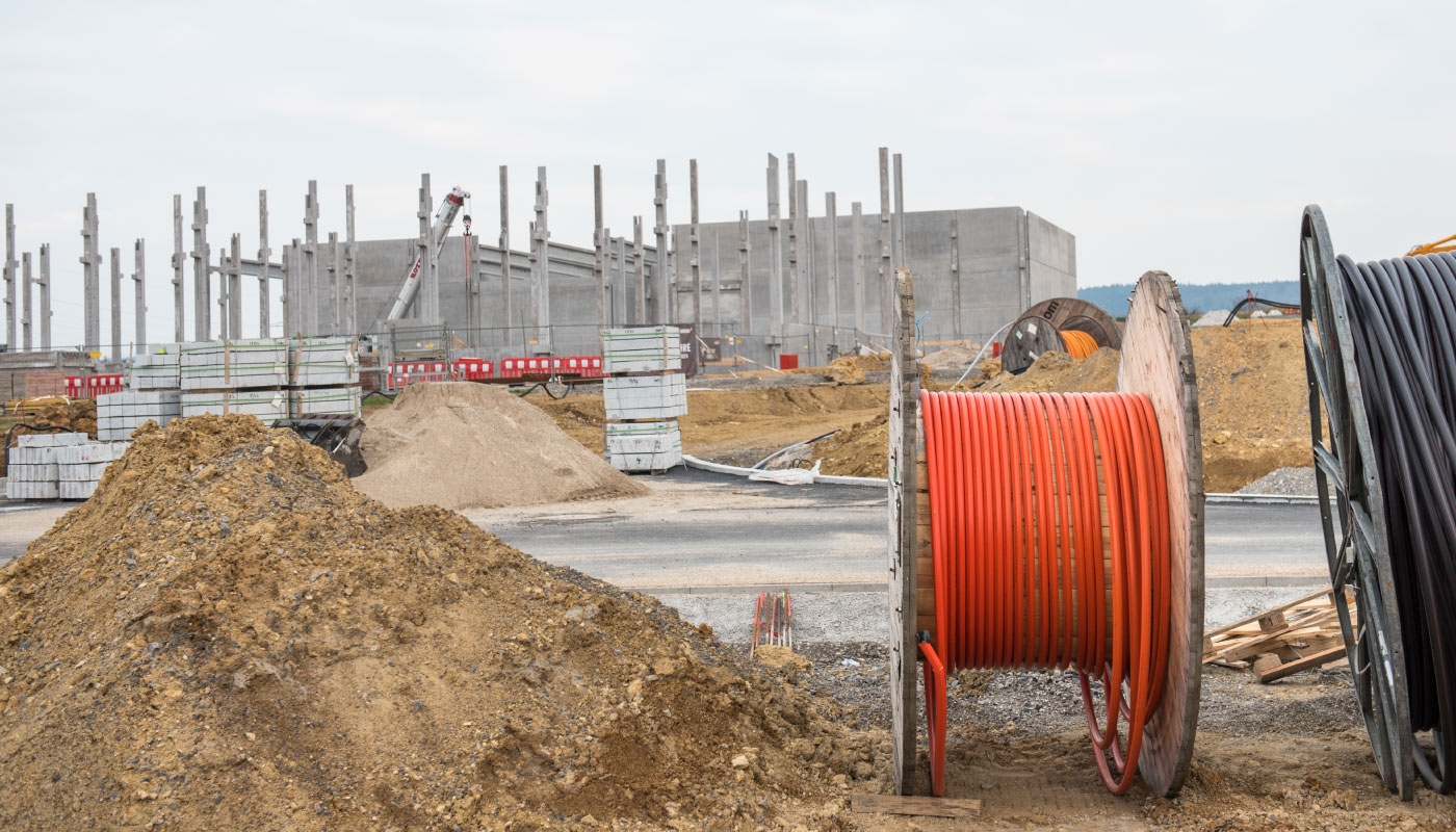 Große Kabelspulen vor einer Baustelle mit unfertigem Betongebäude in Birkenfeld